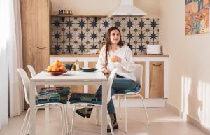 una mujer sentada en una mesa en una cocina en La Camareta Alojamientos Turísticos Rurales, 