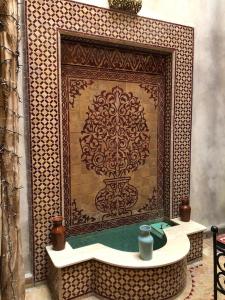 una parete piastrellata con lavandino di fronte a un camino di riad rose eternelle a Marrakech