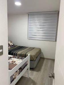 a small bedroom with a bed and a window at Hermoso Departamento familiar en condominio in El Tabo