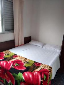 a bedroom with a bed with a flower blanket at Casa de praia em Itanhaem in Itanhaém
