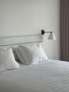 un letto bianco con cuscini bianchi e lampada di Casa da Courela a Cavaleiro