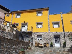 - un bâtiment jaune avec des fenêtres et un mur en pierre dans l'établissement Apartamentos Rurales Parajes de Piedra, à Ibdes