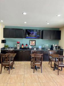 cocina con mesas y sillas de madera y TV en Americas Best Value Inn Sulphur, en Sulphur