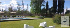 a resort with a pool and chairs and trees at Hotel " Rio Grande " in Malargüe