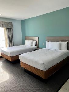 twee bedden in een hotelkamer met blauwe muren bij Americas Best Value Inn Sulphur in Sulphur