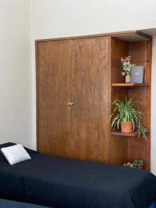 Habitación con cama con puerta de madera y plantas en Alojamiento la salteñita en Salta