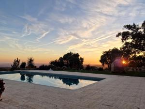 a swimming pool with a sunset in the background at Casa ATMAN in Monchique