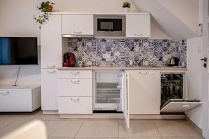 a white kitchen with white cabinets and a tv at Duplex apartmán Pálava in Dolní Dunajovice