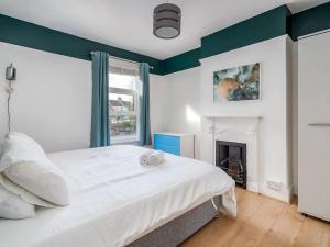 - une chambre avec un lit blanc et une cheminée dans l'établissement "FurnishedRentals Direct" WiggenHouse Stylish 3 Bedroom house Sleeps 8 with Free Parking, 2 Bathrooms, near to Watford High Street and Watford Football Stadium, Suitable for visiting Harry Potter Warner Bros Studio and London, à Watford