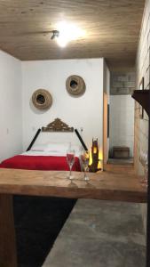 a bedroom with a bed and two wine glasses on a table at Pousada Rosa Bonita in Praia do Rosa