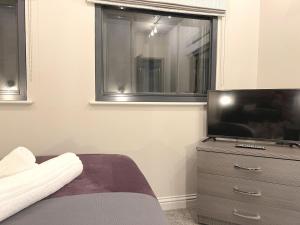 a bedroom with a television and a dresser with a window at Brand New SILVER FORGE - Charming Two Bedroom Apartment - City Centre - Lux Apartment in Birmingham