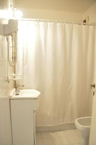 Baño blanco con cortina de ducha y lavamanos en Apart La Posada del Mar en San Bernardo