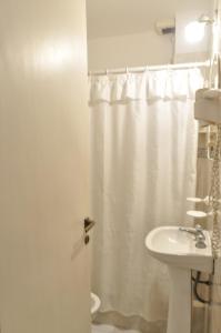 baño con cortina de ducha blanca y lavamanos en Apart La Posada del Mar en San Bernardo