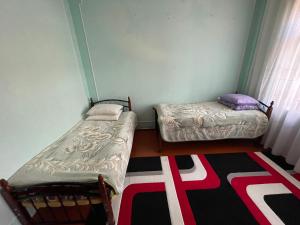 Kleines Zimmer mit 2 Betten und einem Teppich in der Unterkunft Family Guest House in Qusar