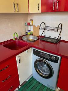eine rote Küche mit einer Waschmaschine und einem Waschbecken in der Unterkunft Family Guest House in Qusar