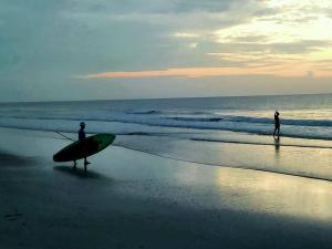 two people standing on the beach with a surfboard at Beachside home, less than 500 steps to beach, oasis yard in Saint Augustine Beach