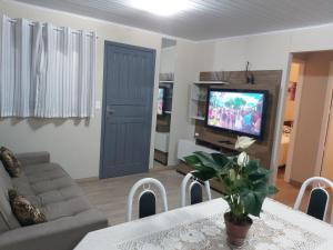 a living room with a couch and a tv at Casa de Temporada Gramado in Gramado