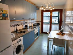 uma cozinha com armários azuis, um lavatório e uma mesa em LA ERIA II, muy luminoso,WIFI, garaje,15 a pie al centro em Oviedo