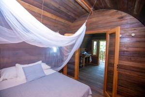 Schlafzimmer mit einem Bett mit Moskitonetz in der Unterkunft ALQUIMIA Hospedaria in Praia do Forte