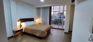 um quarto com uma cama e uma grande janela em Hotel Alba em Ica