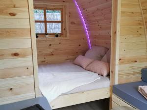 a small bed in a wooden cabin with a purple light at Les Pod Atypique de Sologne - Spa Privatif - Zoo de Beauval in Lanthenay