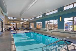 a large swimming pool with a blue wall and windows at Best Western PLUS University Park Inn & Suites in State College