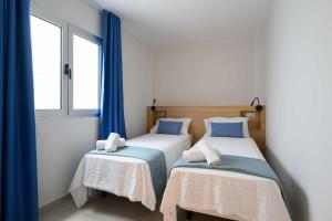 two beds in a room with blue curtains at Canteras Urban Beach in Las Palmas de Gran Canaria