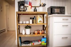 a kitchen with a shelf with food and a microwave at The Nook & Cranny Bsmt Suite, Near WEM & DT, Fast WiFi! Sleeps 4 in Edmonton