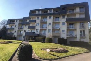 a large apartment building with a lawn in front of it at Studio tout confort in Bagnoles de l'Orne