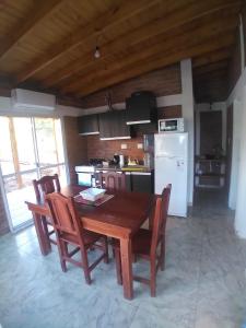 a kitchen with a wooden table with chairs and a refrigerator at Complejo Puesta del Sol san Luis in La Punta