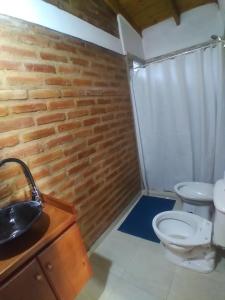 a bathroom with a toilet and a brick wall at Complejo Puesta del Sol san Luis in La Punta +34 photos