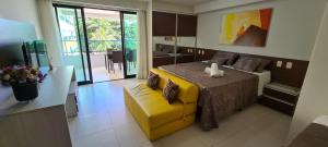 a bedroom with a yellow bed and a yellow bench at Tabatinga Residence Flat beira Mar in Conde