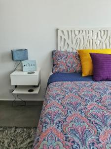 聖薩爾瓦多的住宿－Avitat Joy Cozy&Homy 2B Flat Private Wifi Pool Gym，一间卧室配有一张带色彩缤纷枕头的床和一张桌子