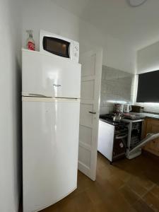 um frigorífico branco com um micro-ondas em cima numa cozinha em Casa de Tati en Cosquín Córdoba em Cosquín