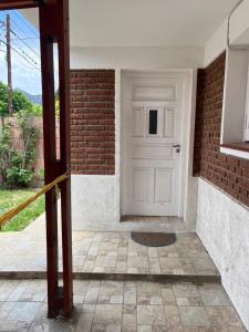 uma porta branca num edifício de tijolos com uma parede de tijolos em Casa de Tati en Cosquín Córdoba em Cosquín