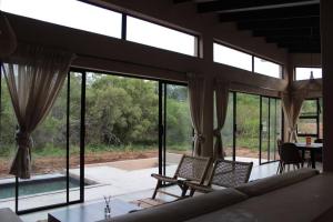 a living room with windows and a table and chairs at Lereko Bush Villa in Marloth Park