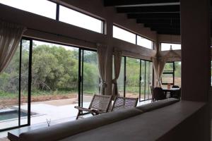 uma sala de estar com duas cadeiras e janelas em Lereko Bush Villa em Marloth Park