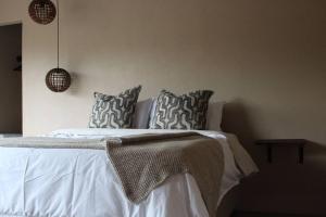um quarto com uma cama com lençóis brancos e almofadas em Lereko Bush Villa em Marloth Park