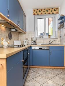 a kitchen with blue cabinets and a window at Haus Seeblick Maritim in Am Schwarzen Busch