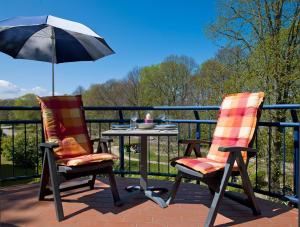2 stoelen en een tafel met een parasol op een patio bij Haus Seeblick Maritim in Am Schwarzen Busch