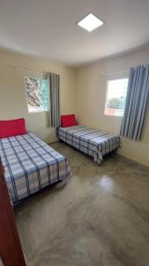 two beds in a room with two windows at Recanto ViVa - Catuama in Goiana