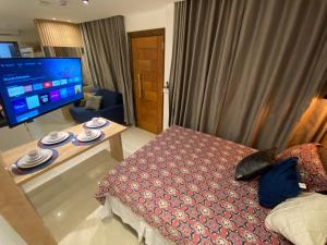 sala de estar con cama y TV en Recanto Novo Premium Flat, en Cabo Frío