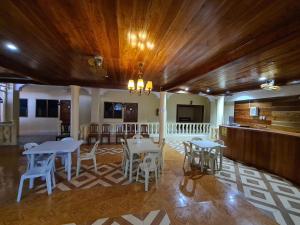 a dining room with white tables and white chairs at La-Familia Guest House in Siquijor