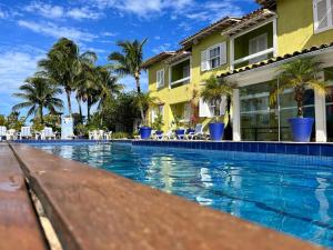 a swimming pool in front of a house with palm trees at Departamento Dos reis in Búzios