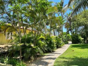 a garden with palm trees next to a yellow building at Departamento Dos reis in Búzios