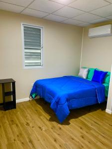 Schlafzimmer mit einem Bett mit blauer Bettwäsche und einem Fenster in der Unterkunft Casitas at Flambohio Beach Camp in Sabana