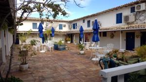 a courtyard with tables and chairs and blue umbrellas at Apartamento no Centro de Búzios in Búzios