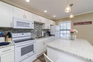 a kitchen with white cabinets and a counter top at Beachside Home, Heated Pool, Steps 2 beach, Meticulous, 5-star Rated in Coquina Gables +32 photos