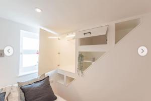 una sala de estar blanca con sofá y estanterías en 1 bedroom modern duplex, en Southampton