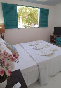 1 dormitorio con 1 cama blanca y ventana en Chalés Jardins dos Cajueiros en Tamandaré